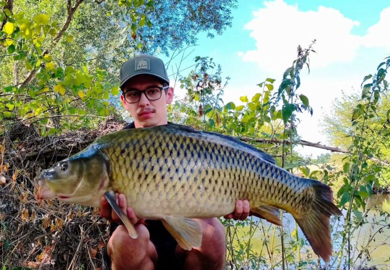 David drží šupinatého kapra uloveného cez deň na rieke Nitre