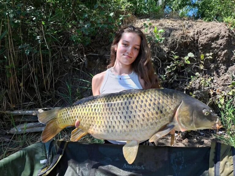 Elizabet drží šupinatého kapra nad podložkou Anaconda, úlovok na boilies AI Carp Shellfish & Plum 24 mm